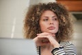 Beautiful white woman with curls thinking about problem solution in front of a computer. Portrait of a freelancer person in though