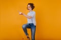 Beautiful white woman in trendy denim pants jumping on yellow background. Joyful female model with wavy hairstyle Royalty Free Stock Photo