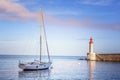Beautiful white yacht on the sea, in the background of a lighthouse and sunset in gentle pink tones Royalty Free Stock Photo