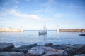 Beautiful white yacht on the sea, in the background of a lighthouse and sunset in gentle pink tones Royalty Free Stock Photo