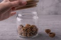 Beautiful whole walnut kernels in a glass jar, a woman's hand lifts a wooden lid.