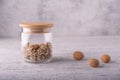 Beautiful whole walnut kernels in a glass jar with a wooden lid, whole nuts in a shell can be seen nearby.