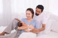 Beautiful wife leaning her back to husband leg while hold newborn with love and carefully, happy Hispanic father with beard or mix Royalty Free Stock Photo