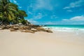 Beautiful and wild lonely beach with rough granite rocks, white sand, palm trees in a jungle and turquoise water Royalty Free Stock Photo