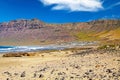 Beautiful wild rough lagoon, secluded white village located at the bottom of a rock face, sand beach, ocean waves  - Playa de Royalty Free Stock Photo