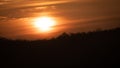 Beautiful wild sunrise over the forest and orange cloudy sky. The sun behind the clouds