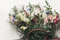 beautiful wildflowers in wicker bag on rustic white wooden background flat lay. colorful flowers in basket in light, space for te Royalty Free Stock Photo