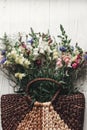 beautiful wildflowers in wicker bag on rustic white wooden background flat lay. colorful flowers in basket in light, space for te Royalty Free Stock Photo