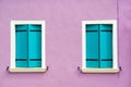 Beautiful windows with turquoise shutters on purple white wall. Colorful houses on Burano island near Venice, Italy Royalty Free Stock Photo