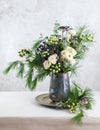 Beautiful winter bouquet in vase. Flower arrangement with roses, fir branches, winter berries, eucalyptus and eryngium. Christmas Royalty Free Stock Photo