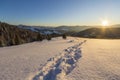 Beautiful winter Christmas landscape. Human footprint track path in crystal white deep snow through empty field, woody dark hills Royalty Free Stock Photo