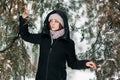 Beautiful winter girl stands in the park between the snowy trees Royalty Free Stock Photo