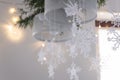 Beautiful winter interior decoration. White knitted snowflakes hang on a chandelier in the Christmas house.