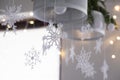 Beautiful winter interior decoration. White knitted snowflakes hang on a chandelier in the Christmas house.