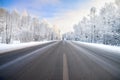 Winter landscape with asphalt road,forest and blue sky. Royalty Free Stock Photo