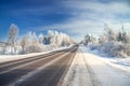 Winter landscape with asphalt road,forest and blue sky. Royalty Free Stock Photo