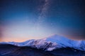 Beautiful winter landscape in the Carpathian mountains. Vibrant night sky with stars and nebula and galaxy. Deep sky