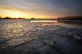 Beautiful Winter landscape with frozen river, reeds and sunset sky.