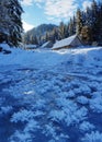 Beautiful winter landscape. Green firs and wooden houses covered with snow and snow crystals over frozen river Royalty Free Stock Photo