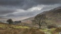 Beautiful Winter landscape image looking along valley from Crimpiau towards Mount Snowdon in the distance