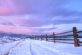 Beautiful winter landscape in the mountains. Sunrise with a colorful sky. Snowy road and wooden fence Royalty Free Stock Photo