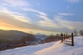 Beautiful winter landscape in the mountains. Sunrise. Snow covered road and wooden fence