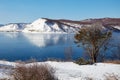 Beautiful winter landscape. Snow-capped mountains are reflected in the unfrozen Angara River Royalty Free Stock Photo