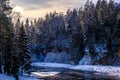 Beautiful winter landscape. Snow-covered banks of a small river in the winter forest at dawn Royalty Free Stock Photo