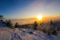 Beautiful winter landscape. The sun sets below the horizon against the backdrop of powdered winter trees atop a snowy mountain