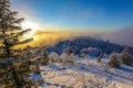 Beautiful winter landscape. The sun sets below the horizon against the backdrop of powdered winter trees atop a snowy mountain