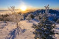 Beautiful winter landscape. The sun sets below the horizon against the backdrop of powdered winter trees atop a snowy mountain