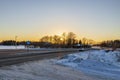 Beautiful winter landscape view. Snowy crossroads and sunset behind forest trees.