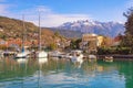 Beautiful winter Mediterranean landscape. Green town and boats in harbor against snow-capped mountains. Montenegro, Tivat Royalty Free Stock Photo