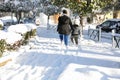 Beautiful winter morning and young woman with child walking on the snow-covered sidewalk of one street in Athens, Greece Royalty Free Stock Photo