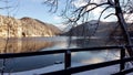 Beautiful winter mountain lake. Railings and trees in front of water and snowy mounts. Royalty Free Stock Photo