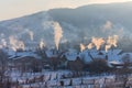 Beautiful winter scenery with smoke coming from house chimneys, on a bright, cold, morning, in remote countryside in Europe