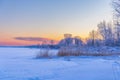 A beautiful winter sunrise scenery of frozen lake and forest. Colorful landscape with dawn skies Royalty Free Stock Photo