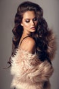 Beautiful winter woman portrait with long wavy hair and vogue style makeup in pink fur coat isolated on studio grey backround. Royalty Free Stock Photo