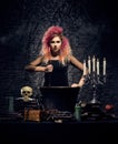 Beautiful witch making witchcraft on a smoky background. Halloween image. Royalty Free Stock Photo