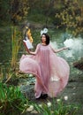 Beautiful witch on swamp holding a burning book and a magic potion