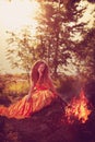 Beautiful witch in the woods near the fire. Magic woman celebrating Halloween. Girl doing witchcraft in the forest.