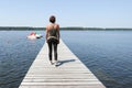 Beautiful woman ahead walks on the pontoon on the lake