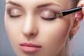 Beautiful woman applying brown eye shadow using makeup brush. makeup for blue eyes Royalty Free Stock Photo