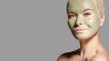 Beautiful Woman Applying Green Facial Mask. Beauty Treatments. Spa Girl Apply Clay Facial mask on grey background Royalty Free Stock Photo