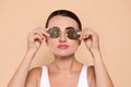 Beautiful woman applying green tea bags on skin under eyes against beige background Royalty Free Stock Photo