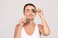 Beautiful woman applying green tea bags on skin under eyes against beige background Royalty Free Stock Photo