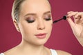 Beautiful woman applying mascara on background, closeup. Stylish makeup Royalty Free Stock Photo