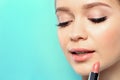 Beautiful woman applying nude lipstick on color background Royalty Free Stock Photo