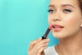 Beautiful woman applying nude lipstick on color background. Royalty Free Stock Photo