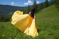 A beautiful woman of Asian appearance in a yellow dress walks in the summer in Altai